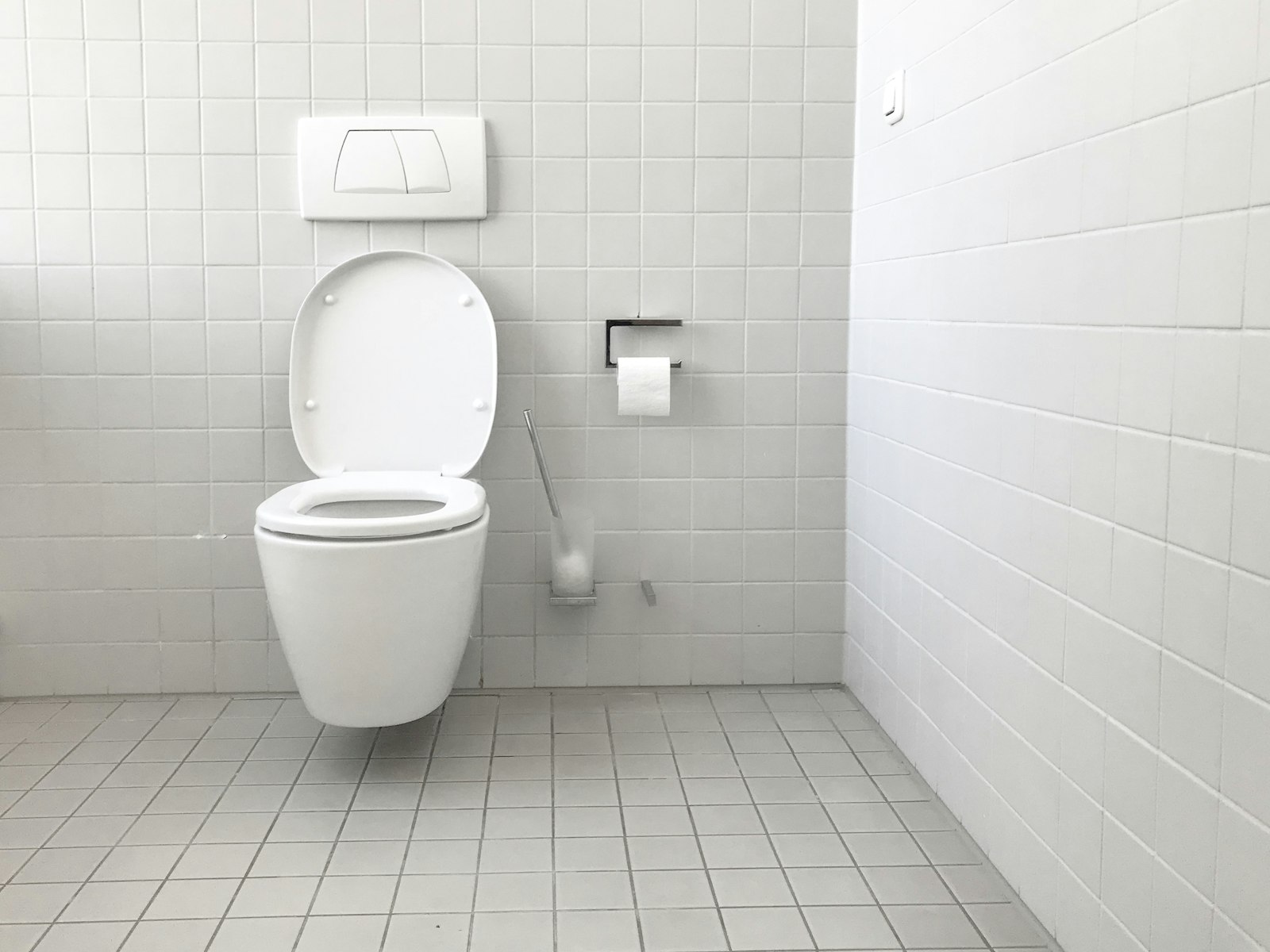 A clean, plainly-tiled bathroom with a floor-mounted toilet